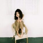 Young woman sitting barefoot on wicker chair