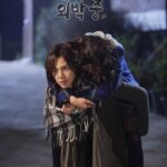 Woman carrying friend piggyback on dimly lit street