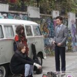 Three people beside vintage van and graffiti wall
