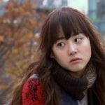 Young woman in scarf outdoors with autumn foliage