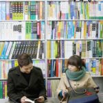 Two people seated on bookstore floor reading books
