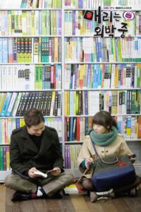 Two people seated on bookstore floor reading books