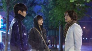 Three people standing on a nighttime city street