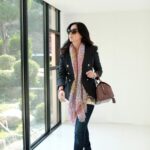 Woman walking by windows wearing scarf, sunglasses