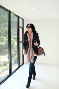 Woman walking by windows wearing scarf, sunglasses