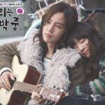 Man plays guitar while woman rests on shoulder
