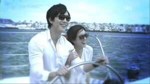 Smiling pair wearing sunglasses steering boat at sea