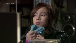 Person holding blue knitted heart, thoughtful expression