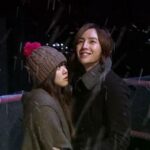 Couple standing on snowy bridge at night