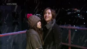 Couple standing on snowy bridge at night
