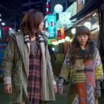 Two women walking on neon-lit street at night