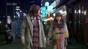 Two women walking on neon-lit street at night