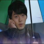 Man holding multicolored umbrella talking on phone