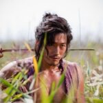 Rugged man with sword in tall grass