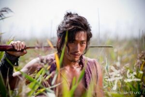 Rugged man with sword in tall grass