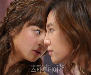 Two women facing each other closely, whispering