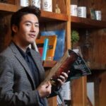 Man holding magazine by wooden bookshelf