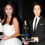 Two formally dressed people holding figurine trophies