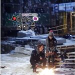 Two people warming hands by small fire