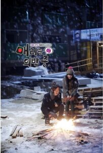 Two people warming hands by small fire