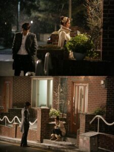 Two people outside brick house in rain