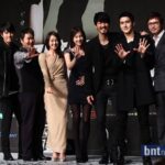 Seven people posing on stage waving hands
