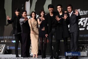 Seven people posing on stage waving hands