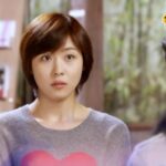 Surprised woman in gray sweater with heart