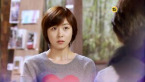 Surprised woman in gray sweater with heart