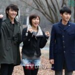Three smiling people outdoors raising their fists
