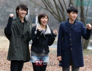 Three smiling people outdoors raising their fists