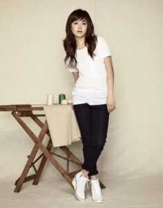 Woman in white t-shirt leaning on wooden table