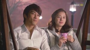 Smiling couple on bench, woman holding mug