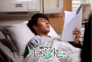 Man resting in hospital bed reading documents