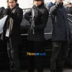 Three men in coats aiming guns