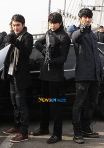Three men in coats aiming guns