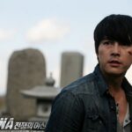 Man with cheek cut looking aside among tombstones