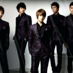Five young men wearing black suits