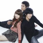 Three smiling young adults holding hands
