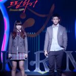 Two people in school uniforms on stage