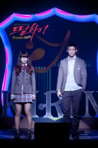Two people in school uniforms on stage