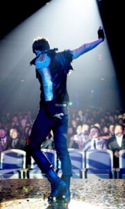 Performer with raised arm on spotlighted stage