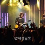 Guitarists performing onstage before cheering crowd