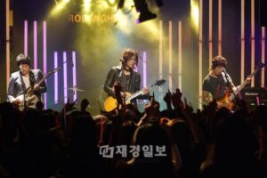 Guitarists performing onstage before cheering crowd