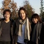 Three smiling people posing outdoors