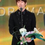Man in tuxedo with bouquet on awards stage