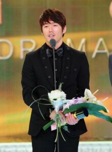 Man in tuxedo with bouquet on awards stage