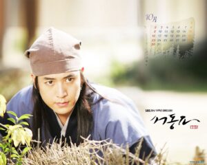 Young man in traditional Korean attire crouching outdoors