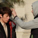 Man adjusting another man's hair outdoors