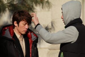 Man adjusting another man's hair outdoors